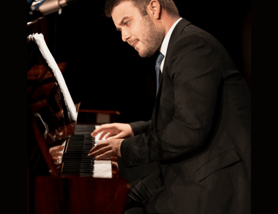 A musician in a smart suit plays the piano