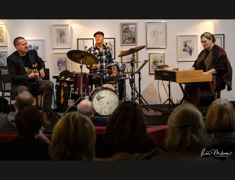 A trio of musicains on stage playing a variety of instuments