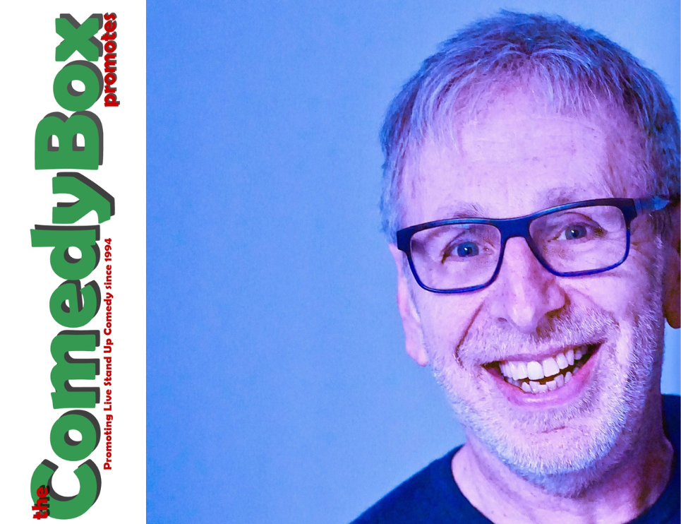 the comedy box. An image of a man with grey stubble & glasses